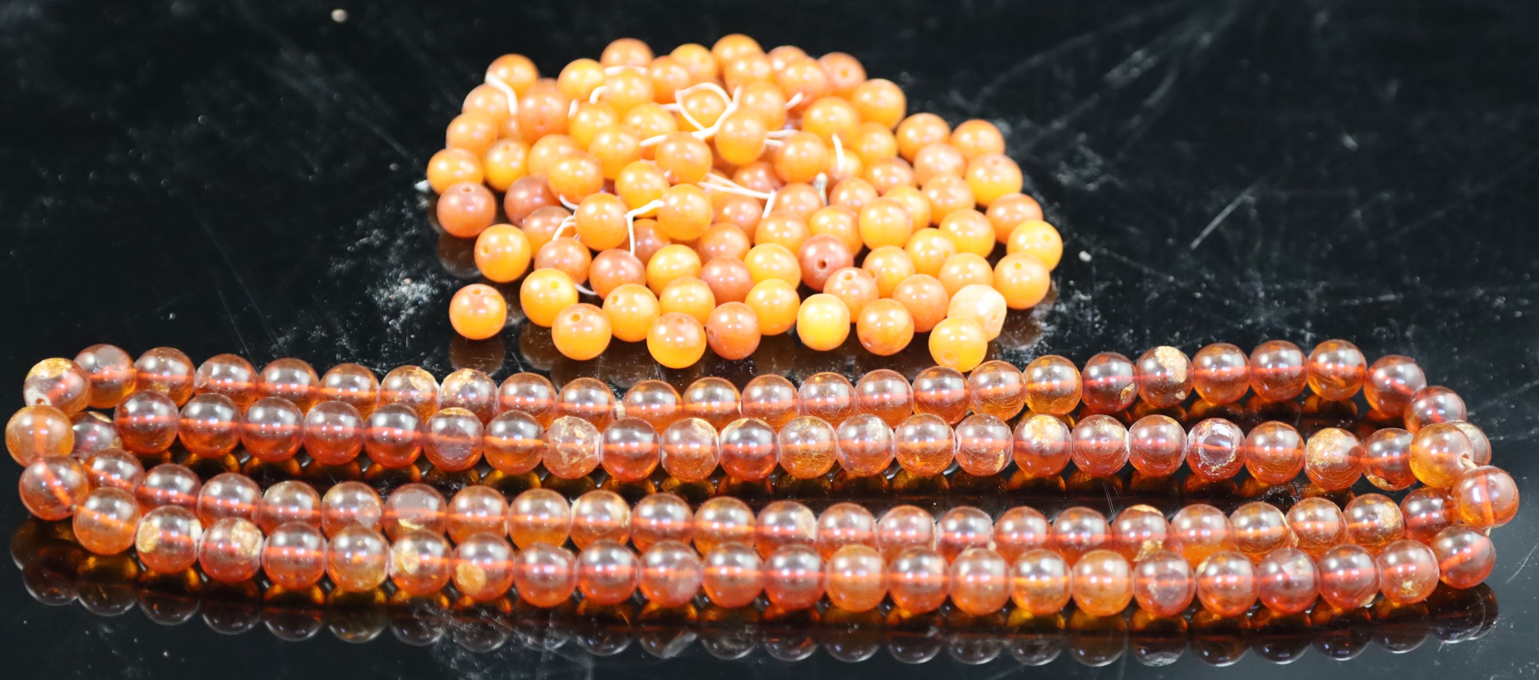 A single strand translucent amber bead necklace, 132cm, gross 153 grams and one other amber necklace (now loose), gross 126 grams.